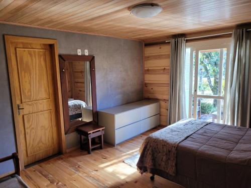 1 dormitorio con cama, espejo y ventana en Chalé Bela Vista, en Gramado