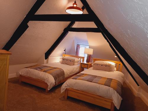 a attic room with two beds and a window at Tubs Cottage in Kingsteignton