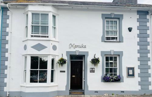 uma casa branca com uma porta preta e janelas em Arosfa Harbourside Guesthouse em Aberaeron