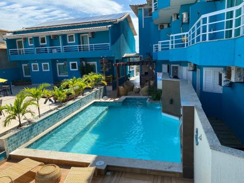 a swimming pool in front of a blue building at Pousada Mirante da Prainha in Arraial do Cabo