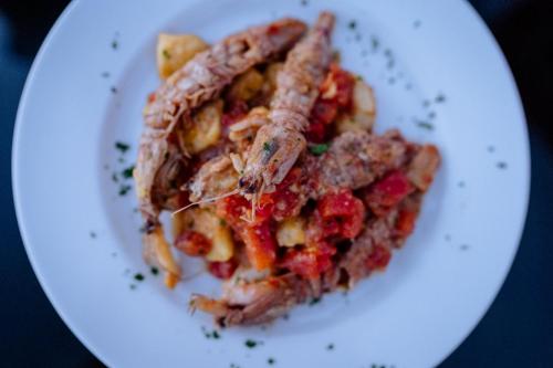 a white plate with a pasta dish with meat and sauce at Faro di Punta Fenaio in Campese