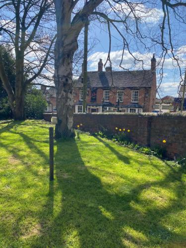 un arbre devant un bâtiment en briques dans l'établissement STABLE COTTAGE, à Cheswardine