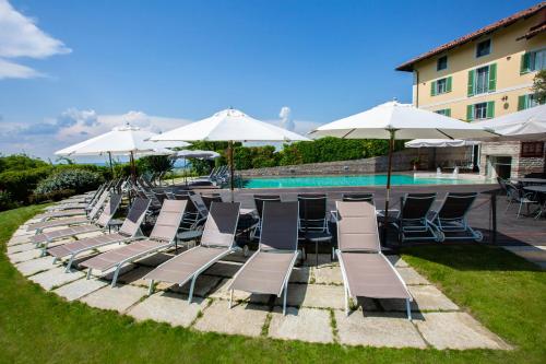 a row of lounge chairs and umbrellas next to a pool at Relais Villa D'Amelia in Benevello