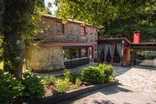 kamienny dom z czerwonymi oknami i dziedzińcem w obiekcie A Pontiga I Casa Rural w mieście Mezonzo