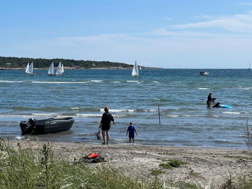 een groep mensen op het strand met zeilboten in het water bij Ny gårdsleilighet i Nevlunghavn in Larvik