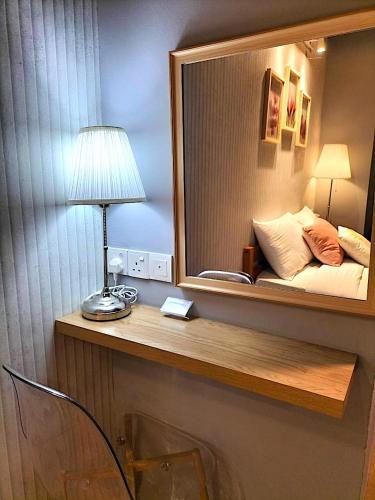 a mirror above a desk with a lamp and a bed at Le Meilleur in George Town