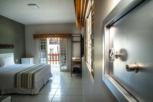 1 dormitorio con 1 cama y puerta que da a un balcón en Villaê Pousada en Pirenópolis