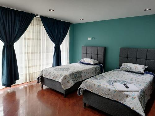two beds in a room with blue walls at Cornelio's House in Bogotá