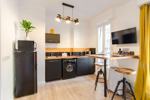 Il comprend une cuisine équipée d'un réfrigérateur noir et d'une table. dans l'établissement #38 Promenade Studio : AC 2 mins de la Plage, à Nice