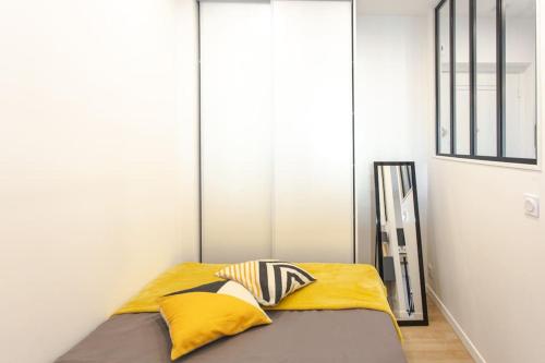 - une chambre avec un lit doté d'oreillers jaunes et gris dans l'établissement #38 Promenade Studio : AC 2 mins de la Plage, à Nice