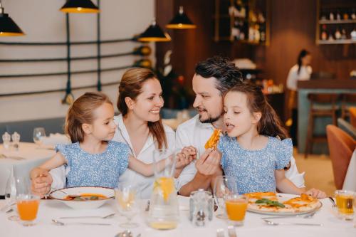 a family eating pizza at a table in a restaurant at Hotel Linea Mare in Pobierowo