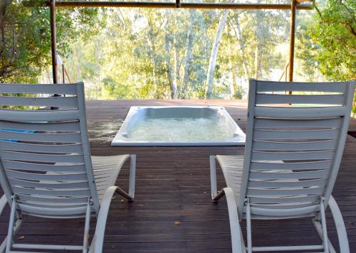 two chairs and a hot tub on a deck at Stonehill River Lodge by Dream Resorts in Buffeljagsrivier