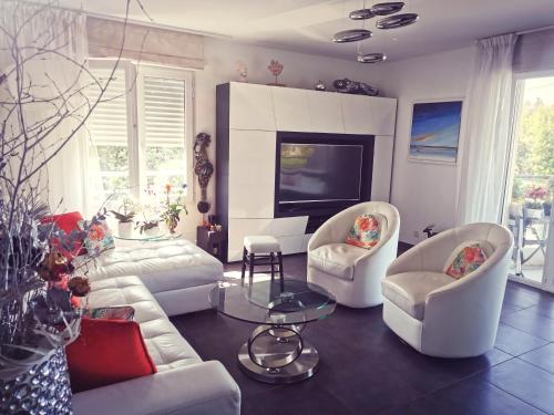 a living room with a couch and chairs and a tv at Bleu Turquoise in Saint-Raphaël