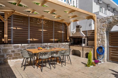 un patio al aire libre con mesa de madera y sillas en Villa Privilege Kalamaki, en Kalamaki