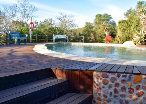 a swimming pool with a wooden deck next to a wooden at Stonehill River Lodge by Dream Resorts in Buffeljagsrivier