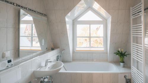 bagno con vasca, lavandino e finestra di Lieblingsapartment No.9 in Top-Lage für 2 Gäste a Rostock