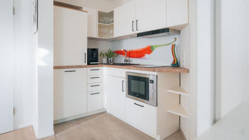 een keuken met witte kasten en een magnetron bij Lieblingsapartment No.9 in Top-Lage für 2 Gäste in Rostock