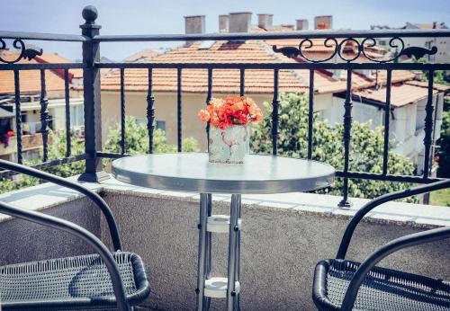 a table with a vase of flowers on a balcony at Bogdanovi Guest House in Chernomorets