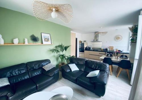 Il comprend un salon avec un canapé en cuir noir et une cuisine. dans l'établissement Émerveillez-vous en Ardèche, à Privas
