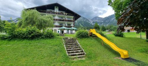 a house with a yellow slide in the grass next to a building at Hotel Stierer in Ramsau am Dachstein
