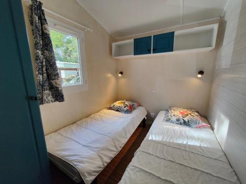 deux lits dans une petite pièce avec une fenêtre dans l'établissement Bungalow cosy à 300m de l’océan, à Bretignolles-sur-Mer