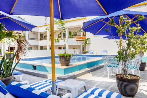 una piscina con sillas y sombrillas azules y blancas en Hotel Pueblito Vallarta en Puerto Vallarta