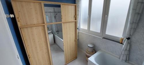 ein Badezimmer mit einer Holztür neben einer Badewanne in der Unterkunft Les Marronniers 30 in Berck-sur-Mer