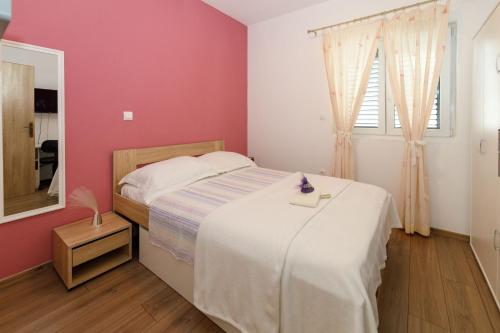 1 dormitorio con cama blanca y pared rosa en Blue home en Makarska