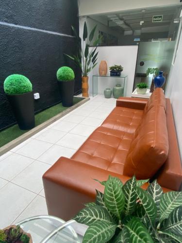a brown leather couch in a room with plants at Bianca Praia Hotel in Recife