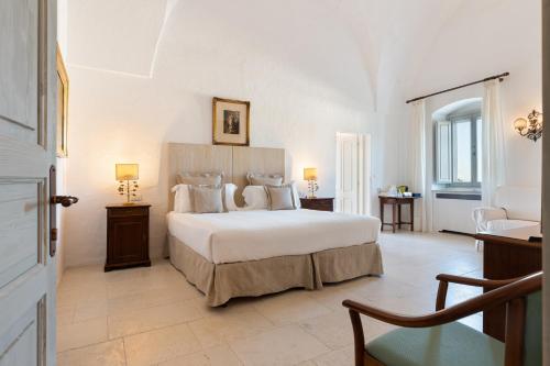 a bedroom with a large white bed and a chair at Masseria Le Carrube in Ostuni