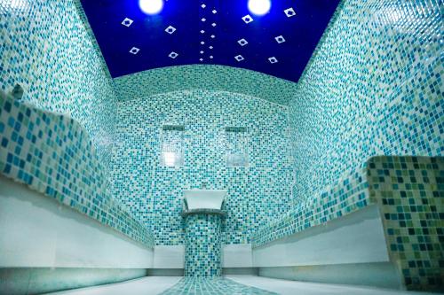 ティラナにあるDoanesia Premium Hotel & Spaの青いタイル張りの壁と照明付きの天井が特徴の客室です。