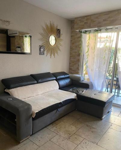 uma sala de estar com um sofá e um relógio na parede em Joli T2 ,50 m des plages, 4 pers , en rez de jardin em Fréjus