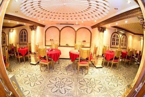 comedor con mesas y sillas rojas y techo en The New Garden Palace Hotel en El Cairo