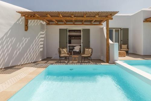 a villa with a swimming pool and a table and chairs at Aya Sofia Suites in Mýkonos City