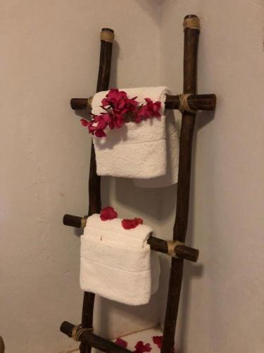 a towel rack with towels and flowers on a wall at chale aparecida dos milagres in São Miguel dos Milagres