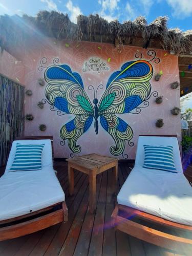 a mural of a butterfly on a wall next to two beds at chale aparecida dos milagres in São Miguel dos Milagres