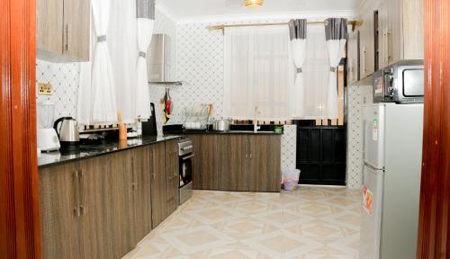 cocina con armarios de madera y nevera blanca en Advent Homes on Moi South lake road, Villa View Estate en Naivasha