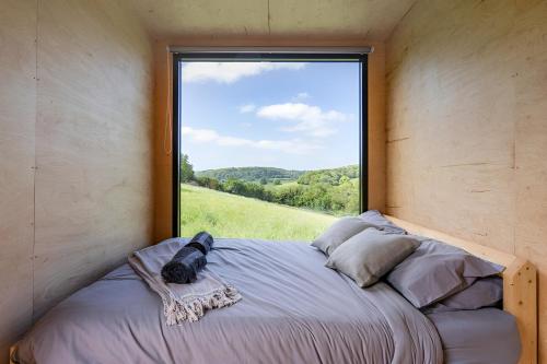 坎特伯雷的住宿－Secluded Offgrid Cabin w/ Sunset View & Fireplace，一张位于带大窗户的房间内的床铺