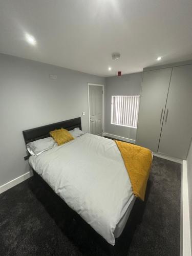 a bedroom with a large bed with white sheets and yellow blankets at Royal Apartments in Thornaby on Tees