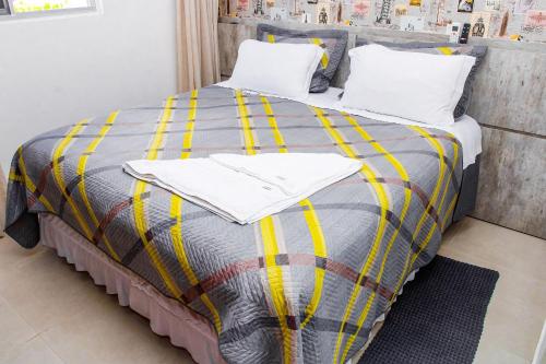 a bed with yellow and gray blankets and pillows at Apartamento sofisticado, confortável e bem equipado - Loft Felau in Cuiabá