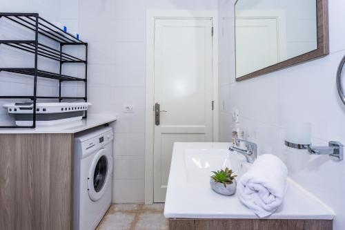 una cucina bianca con lavatrice e lavandino di Eslanzarote ECO TANA HOUSE, super wifi, Tv satélite, Bbq a Playa Honda