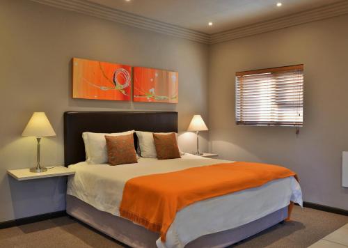 a bedroom with a bed with an orange blanket at Stonehill River Lodge by Dream Resorts in Buffeljagsrivier