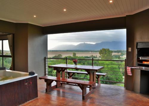 a kitchen with a table and a balcony with a view at Stonehill River Lodge by Dream Resorts in Buffeljagsrivier
