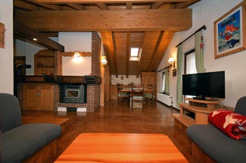 a living room with a couch and a tv and a fireplace at La Mansarda in the Dolomites Jacuzzi in Santo Stefano di Cadore