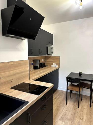 une cuisine avec des armoires noires et une table avec une cuisinière dans l'établissement Appartement St-Malo Intramuros, à Saint-Malo