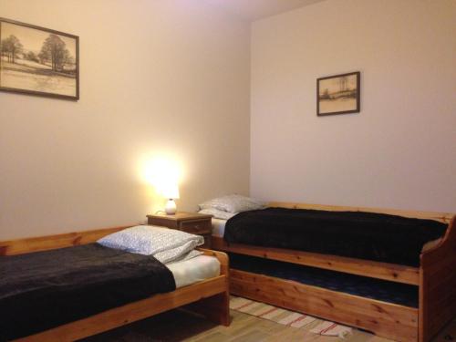 two beds in a room with a lamp on a table at W Starym Sadzie in Owińska