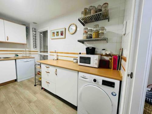 a kitchen with a washer and a microwave on a counter at Apartamento Torre Atalaya-Teatinos Malaga capital in Málaga