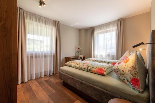 1 dormitorio con 1 cama y 2 ventanas en Apartments Karbon, en Castelrotto