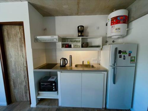 una pequeña cocina con refrigerador y fregadero en Monoambiente vista lateral en Pinamar en Pinamar