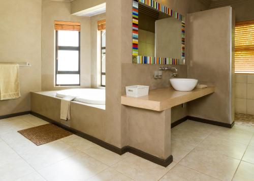 a bathroom with a bath tub and a sink at Stonehill River Lodge by Dream Resorts in Buffeljagsrivier
